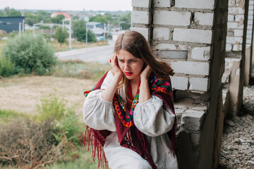 Art work on the theme of the war in Ukraine. A crying Ukrainian woman in national dress sits in the window frame of a building bombed by the Russian army.