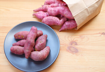 Plate of Raw Purple Sweet Potatoes with Some Scattered from Paper Shopping Bag