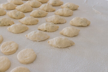 Fototapeta na wymiar Preparation for baking buns with stuffing and donuts on white countertop using of yeast dough