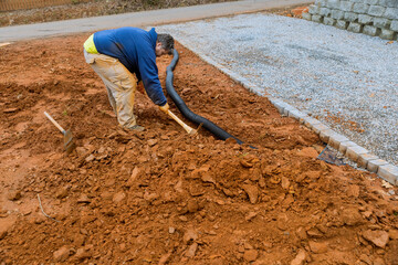 When heavy rains are predicted worker digs trench so drainage pipes can be laid during rainy season