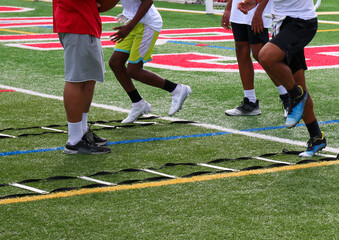 Legs of football players running through ladder drills at summer camp