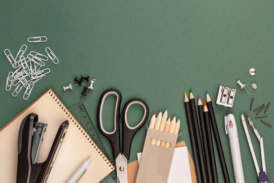 stationery items around of image on green background. Back to school background, banner with copy space. Student's or engineer's supplies. Office objects on dark green background. Calculator, keyboard
