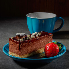 Three chocolates cake with chocolate drips on a black background. Layered cake with milk, black and white chocolate souffle decorated with strawberries on top. Confectionery background with copy space