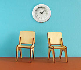 Waiting room with empty wooden chairs and wall clock. Two stools in the room
