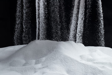 White quartz sand pours on a black background