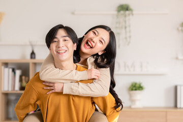 Asian young couple hugging with positive emotion and loving together at warmth place. Attractive man and woman embracing spending time together at home. Couple love and Valentine's Day concept - obrazy, fototapety, plakaty