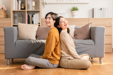 Asian young couple smile and laughing with positive emotion and loving together at warmth place. Attractive man and woman spending time together at home. Couple love and Valentine's Day concept