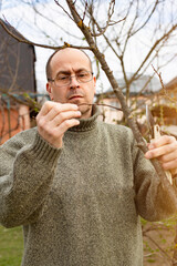 Caucasian gardener pruning trees at backyard spring time