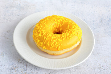 mango donut with sugar sprinkles isolated on white saucer, close-up