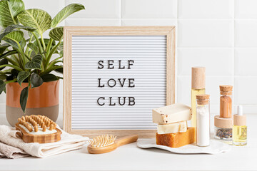 Bathroom styling and organization. Letter board with text Self Love Club. Organic lifestyle and skin care products.