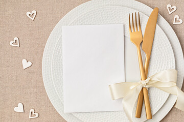 Festive wedding, birthday table setting with golden cutlery and porcelain plate. Blank card mockup....