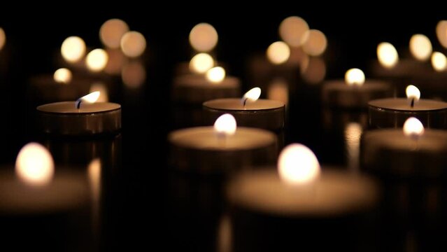 Many candles burn in the dark. Memorial day with candles. Lighted memorial candles. Funeral candles close-up.