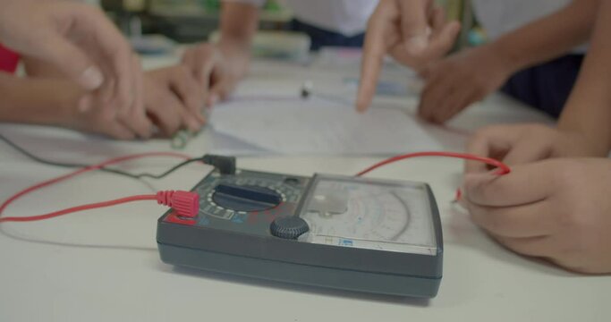 The group of Asian high school students are studying scientific experiment about electric current measurement in scientific laboratory.