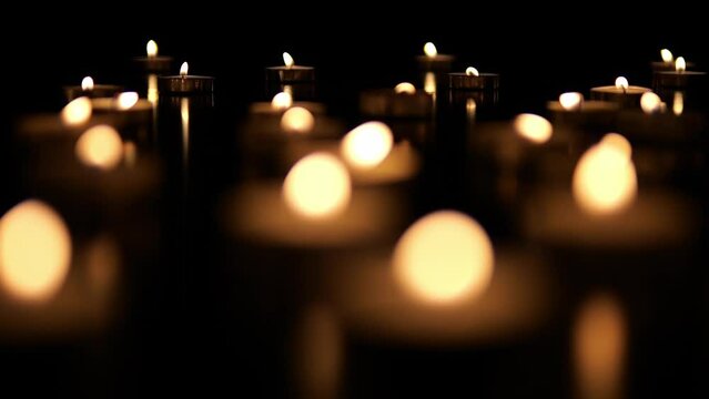 Many candles burn in the dark. Memorial day with candles. Lighted memorial candles. Funeral candles close-up.
