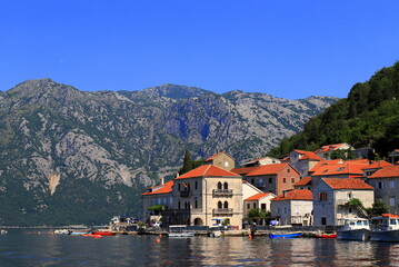 Fototapeta na wymiar Perast Montenegro. Old Historic buildings, beautiful resort town in Kotor Bay in summer near high mountains. Montenegro