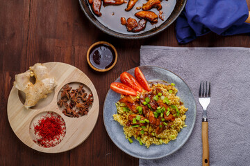 Fried chicken pieces with rice in soy and pad thai sauce on the table with other food and spices.