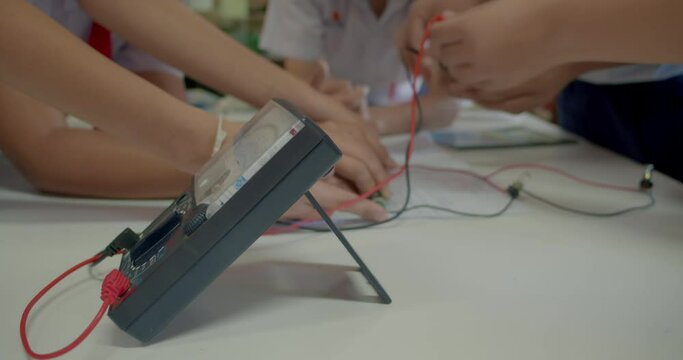 The group of Asian high school students are studying scientific experiment about electric current measurement in scientific laboratory.