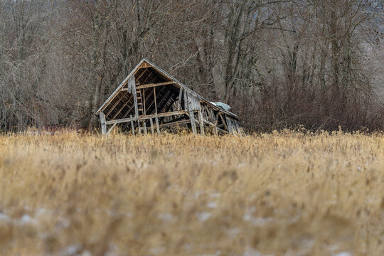 Abandoned derelict shack falling apart at edge of brown field