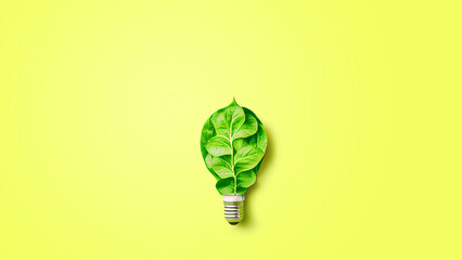 Green energy concept. Energy saving technology, light bulb with green leaves on yellow background