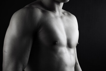 Fototapeta na wymiar Close up view of sexy body of young man with six pack muscular and athletic body on black background. concept of health care, exercise, fitness, muscle mass, health supplements.