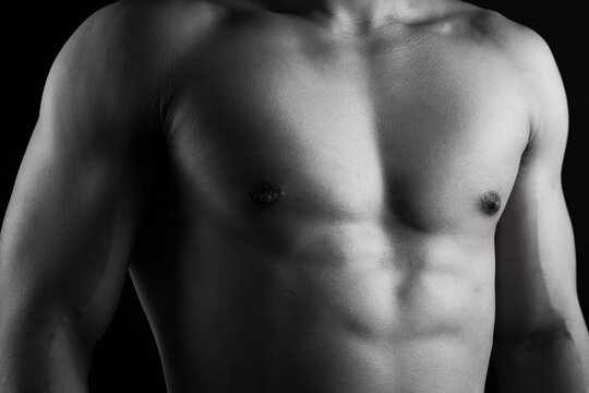 Close up view of sexy body of young man with six pack muscular and athletic body on black background. concept of health care, exercise, fitness, muscle mass, health supplements.
