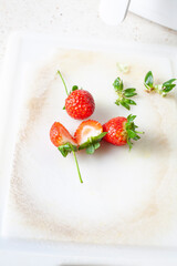sliced ​​strawberries and whole strawberries on cutting board, kitchen tools in background