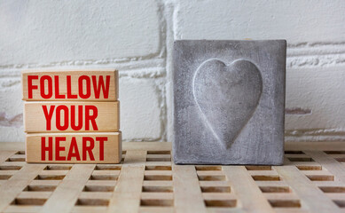 Follow your heart word written on a wooden block with a vintage heart candle.