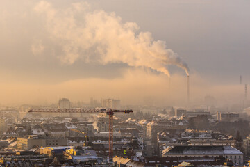 City view of Graz in Austria with buildings, cranes and an industrial plant with smoking chimneys...