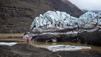 woman standing in front large blue glacier of svínafellsjökull in iceland; huge blue glacier in front of little girl