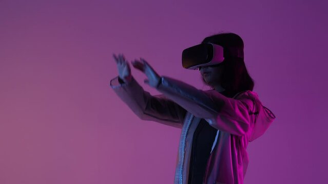 Woman in futuristic costume. Female in modern VR glasses interacting with network while having virtual reality experience. Augmented reality game, future technology, AI concept. VR. Neon light.