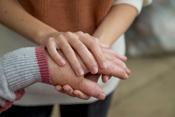 The hands of a young girl hold the bitches of her elderly grandmother. The concept of love and care for the elderly, respect within the family and acceptance of old age