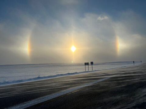 Winter sun dogs across frozen rural fields and road