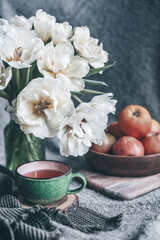 still life flowers in a vase tulips and red apples on a plate