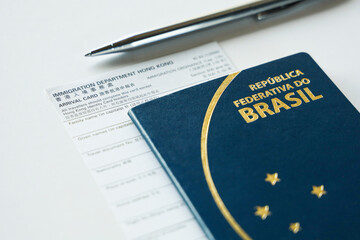 HONG KONG, CHINA, FEBRUARY 2020 - Tourist filling arrival card at Hong Kong immigration checkpoint at the airport. The scene shows an arrival card, a Brazilian passport and a ballpoint pen. - obrazy, fototapety, plakaty