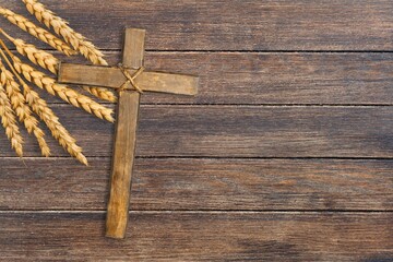 Wood cross and golden wheat on desk