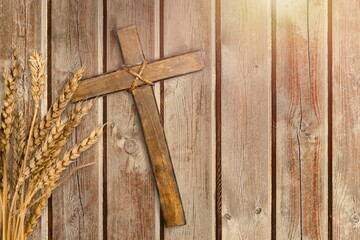 Wood cross and golden wheat on desk