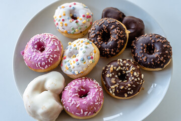 Assorted ring doughnuts covered in icing and sprinkes