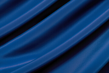 The texture of a luxurious smooth fabric in blue, purple with folds and waves. Blue fabric, material