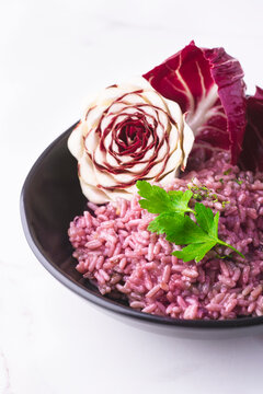 Risotto with radicchio, winter Nord Italy dish. Radicchio cicory  (Radicchio rosso di Treviso, Veneto)  on the white table. Winter recipes from the north Italy, close up