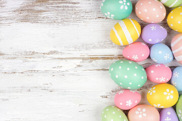 Pastel colored Easter egg side border. Top down view over a rustic white wood background. Copy space.