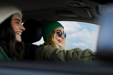 Fototapeta na wymiar Happy female friends driving a car with the blue sky in the background