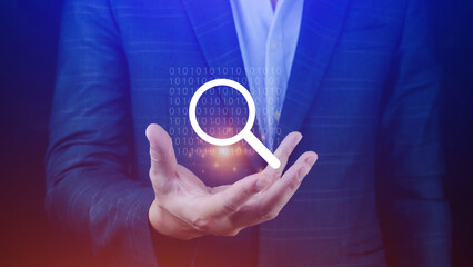 Businessman holding magnifying glass icon hologram in hand. Technology business and job search...