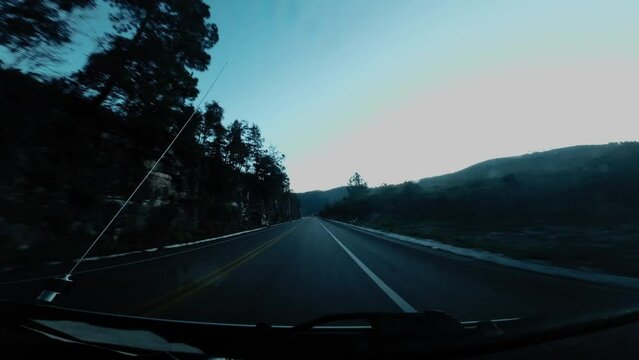 Viajando por la carretera de autopista en un atrdecer, la carretera y el asfalto est&aacute;n gises con un contraste alto