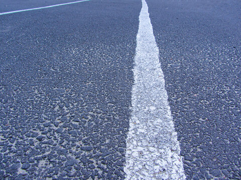 Road top view with lines painted in white colour continuous across length of Road , dividing lines for both side traffic on highway