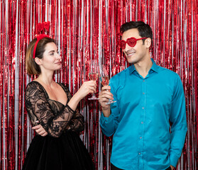 Beautiful and happy couple celebrating Valentine's Day together and drinking champagne over festive background