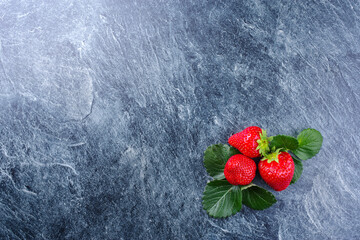Reife rote Erdbeeren aus biologischem Anbau angeboten als Draufsicht auf einem grauen Board mit...