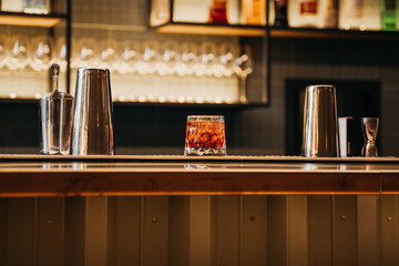  glass of aperol syringe stands on the bar counter, the bar is in the background