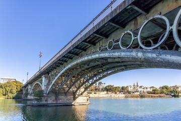 View of the Isabel II Bridge, popularly known as Puente de Triana, is a bridge located in Seville. It joins the city center with the Triana neighborhood, crossing the Guadalquivir river.