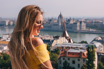 Fototapeta na wymiar A cheerful woman looks at the parliament in Hungary, visits the sights of Budapest