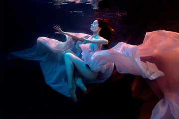 Sensual woman model, ballerina swimming underwater in a fluttering dress. Soft blurred focus. Fairy tale